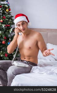 Sexy man in the bed wearing santa hat in christmas concept