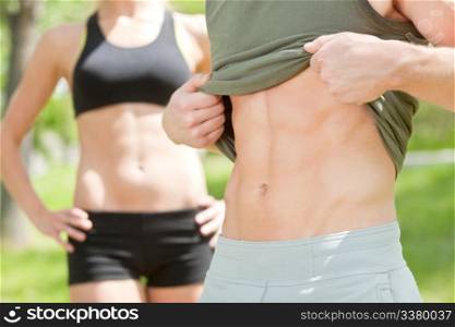 Sexy man showing his six-packs while woman standing in background