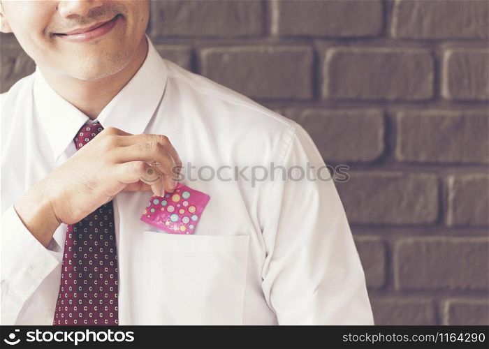 Sexy man smiling holding condom from his pocket. Safe sex Concept.
