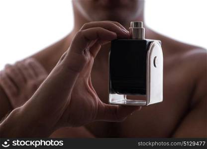 Sexy man with bottle of perfume in low key photo