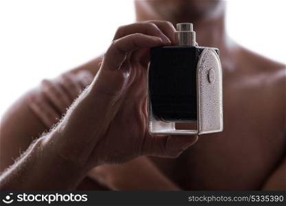 Sexy man with bottle of perfume in low key photo