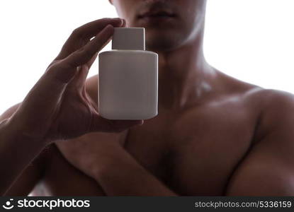 Sexy man with bottle of perfume in low key photo