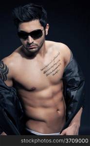 Sexy man with great abs over black isolated background wearing sunglasses
