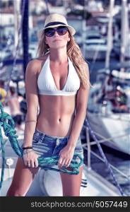 Sexy model posing on sailboat with sailing equipment, happy traveler working on the yacht, luxury summer photoshoot concept