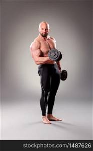 Sexy muscular bodybuider posing with weights on the gray background