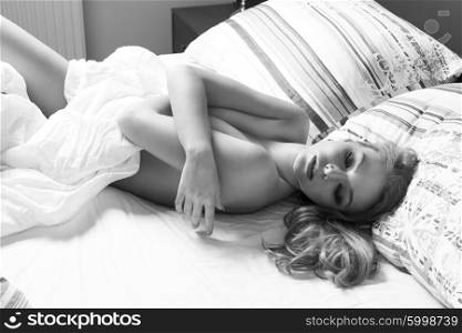 sexy naked woman . laying down on bed , she has blond hair and covering with sheet , she has closed eyes.in black and white&#xA;