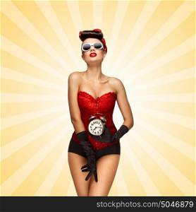 Sexy pinup girl in a red vintage corset holding a retro alarm clock in her hand and posing on colorful abstract cartoon style background.