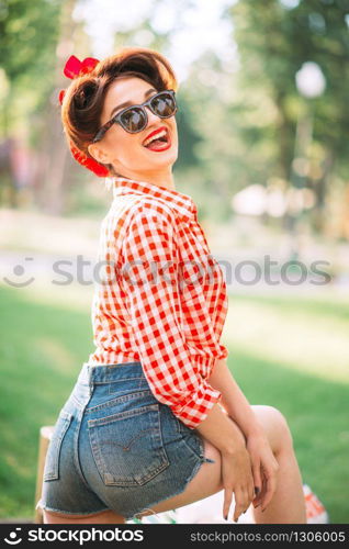 Sexy pinup girl in denim shorts and sunglasses outdoors, retro american fashion. Attractive woman in pin up style. Sexy pinup girl outdoors, retro american fashion