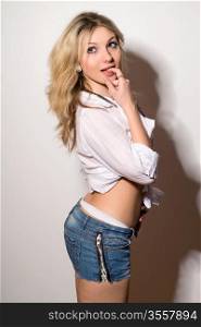 Sexy playful blond young woman in a white shirt