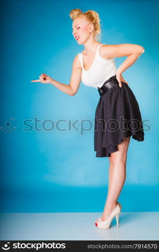 Sexy retro girl full length. Pin up woman with blonde hairdo and shaking wagging her finger gesture sign on blue background in studio.