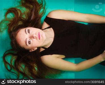 Sexy seductive woman wearing black dress in swimming pool water. Young attractive alluring girl floating. Top view.. Sexy seductive woman in black dress in water.