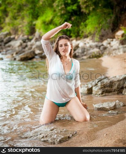 Sexy slim woman watering herself on sea shore