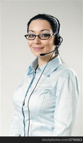 Sexy smiling call center operator portrait. Sexy girl wearing headset and glasses standing on uniform background. One of a series.