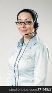 Sexy smiling call center operator portrait. Sexy girl wearing headset and glasses standing on uniform background. One of a series.
