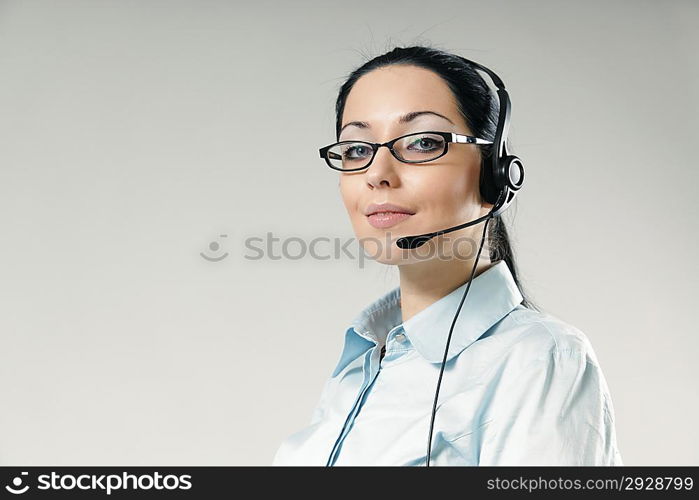 Sexy smiling haughty call center operator portrait. Sexy girl wearing headset and glasses standing on uniform background. One of a series.