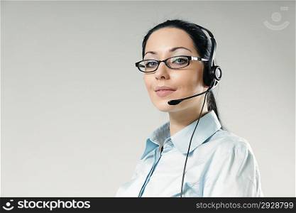Sexy smiling haughty call center operator portrait. Sexy girl wearing headset and glasses standing on uniform background. One of a series.