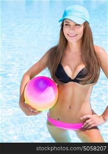 Sexy sportive girl having fun in swimming pool with ball, enjoying luxury beach resort, active summer vacation, sport and enjoyment concept