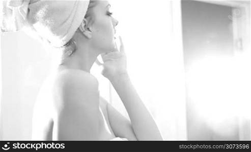 sexy woman after shower looking at the window wearing towels