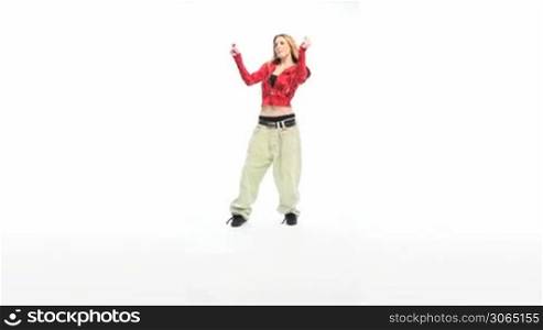 Sexy Woman Dancing in red top and baggy pants with hands raised in rythm to the music.