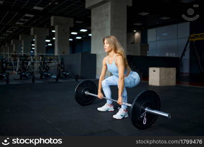 Sexy woman doing exercise with barbell, fitness training in gym. Athletic female person on workout, sportswoman in sport club, active healthy lifestyle, physical wellness. Sexy woman doing exercise with barbell in gym