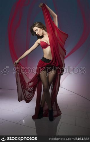 sexy woman in dancer pose and flying hair wearing red lingerie and long fluttering skirt