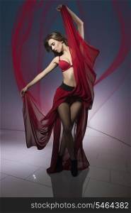 sexy woman in dancer pose and flying hair wearing red lingerie and long fluttering skirt
