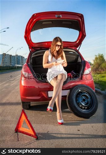 Sexy woman in short dress browsing on tablet how to change wheel