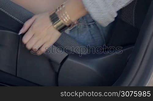 Sexy woman in shorts adjusting height of driver&acute;s car seat with manual stick