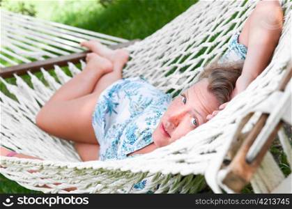 sexy woman is lying in hammock and looking at camera