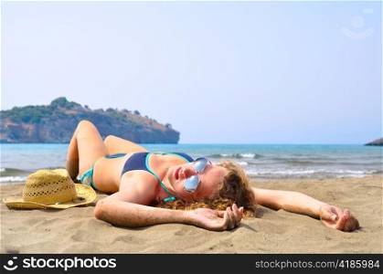 sexy woman is lying on the beach and looking at camera