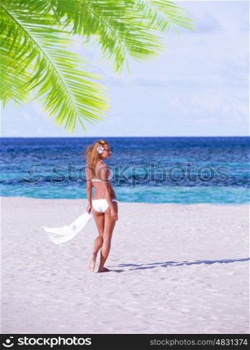Sexy woman on the beach, slim attractive model walking away from camera, relaxation on Maldives resort, summer vacation concept