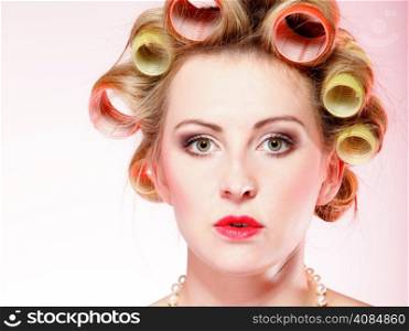 Sexy woman preparing to party, girl with curlers in hair and beads pink background