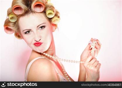 Sexy woman preparing to party having fun, girl in underwear curlers in hair with beads pink background
