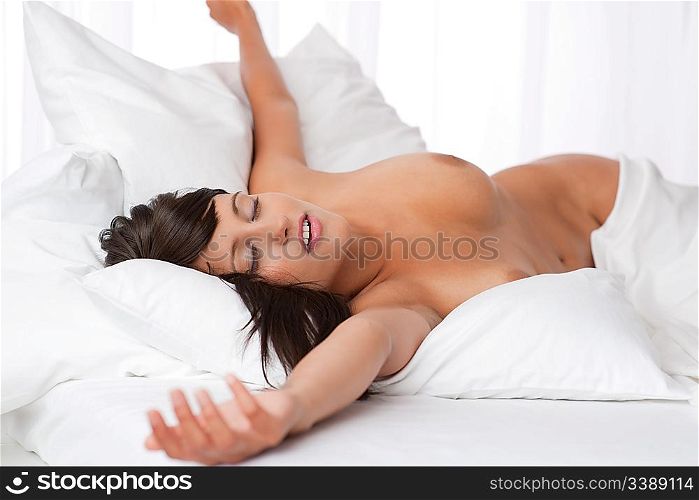 Sexy woman relaxing naked in white bed, shallow DOF