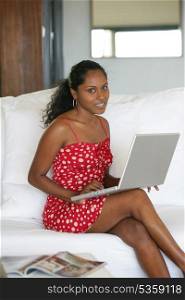 Sexy woman sitting on a sofa and typing on her laptop