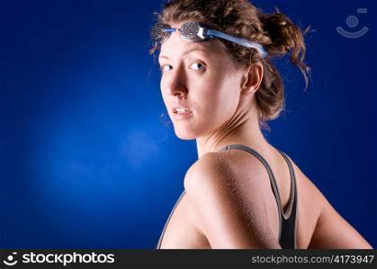 sexy woman swimmer is looking at camera, on blue background
