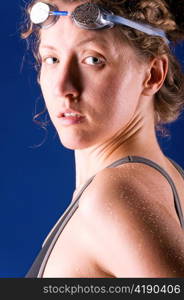 sexy woman swimmer is looking at camera, on blue background