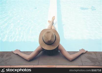 Sexy woman wear bikini and big hat relaxing in the pool.
