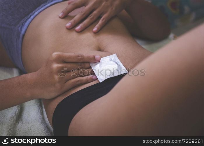 Sexy woman with condom package under hand , Having sex with condom and not getting pregnant