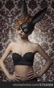 sexy woman with lace stylish lingerie posing with bizarre bunny mask in glamour portrait. Dark Easter