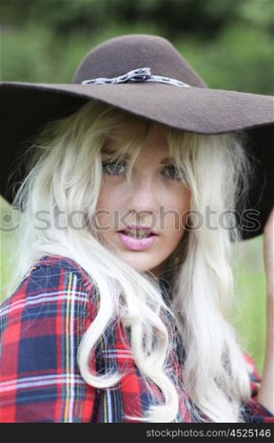 Sexy woman with long blonde hair wearing a hat and checked shirt