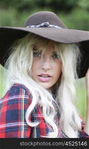 Sexy woman with long blonde hair wearing a hat and checked shirt