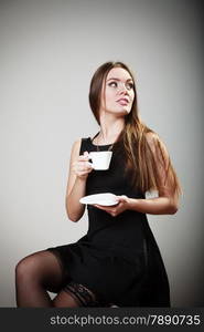 sexy young girl in stockings holding cup of coffee drinking on gray