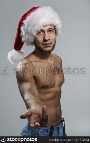 Sexy young man wearing Santa Claus hat welcoming portrait