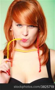 Sexy young woman holding candy. Redhair cute funny girl with sweet jelly on green