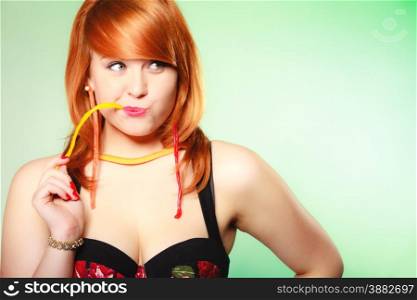 Sexy young woman holding candy. Redhair cute funny girl with sweet jelly on green