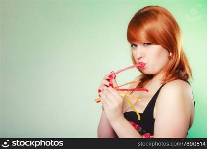 Sexy young woman holding candy. Redhair cute girl with sweet jelly on green.