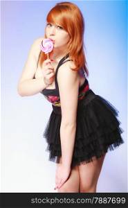 Sexy young woman holding candy. Redhair cute girl with sweet lollipop on blue