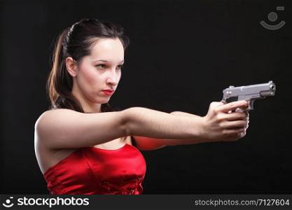 Sexy young woman in red with a gun on black background