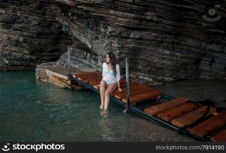Sexy young woman in white shirt sitting in sea cave